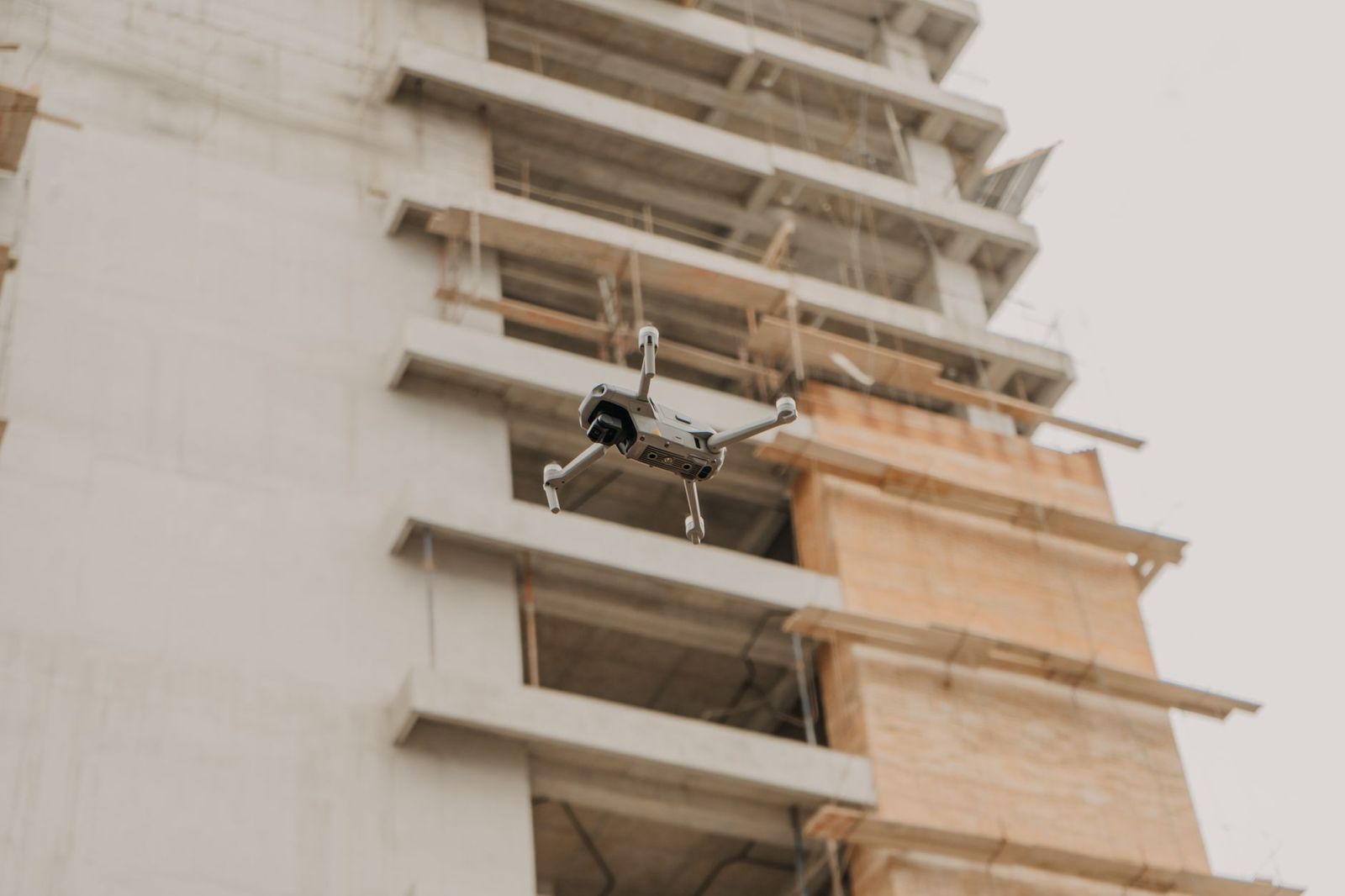 A drone hovering beside a concrete building under construction