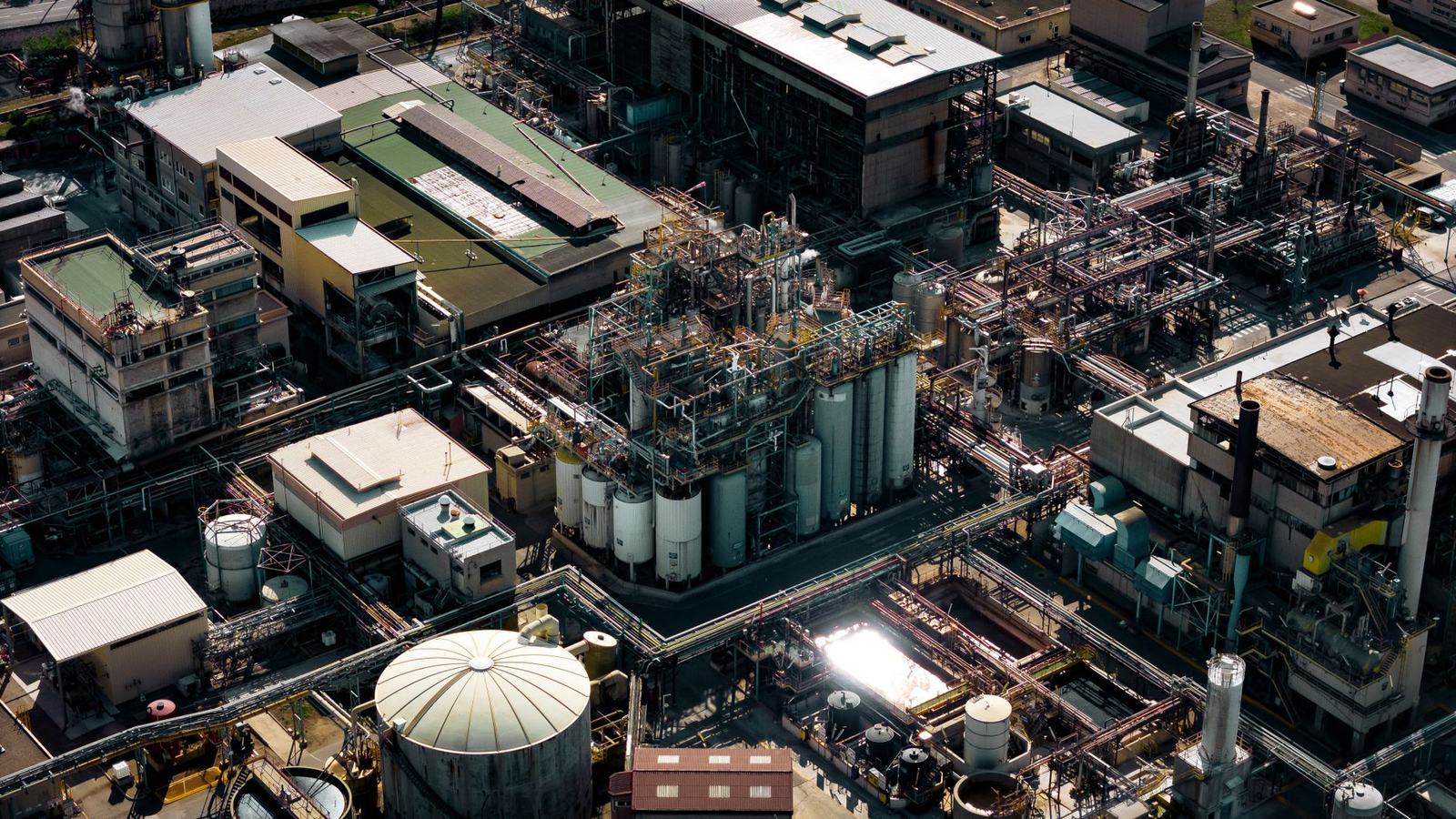 Aerial view of a dense industrial plant with tanks, pipework and roofs