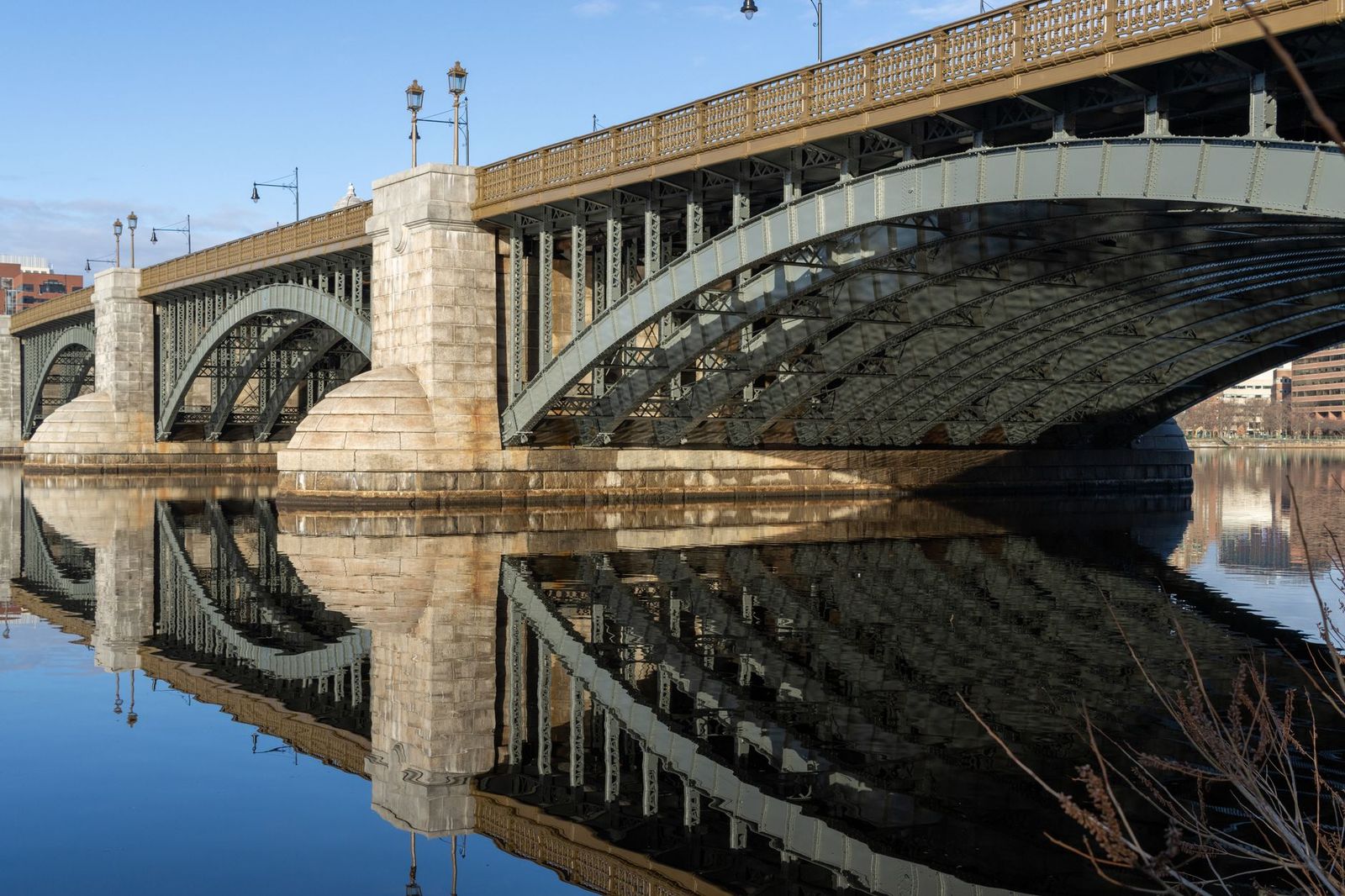 Bridge with stone piers and steel arches reflected in calm water